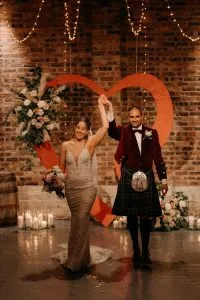 fraoch floral design bride & groom- just married. in the background a heartyshaped arch with flowers