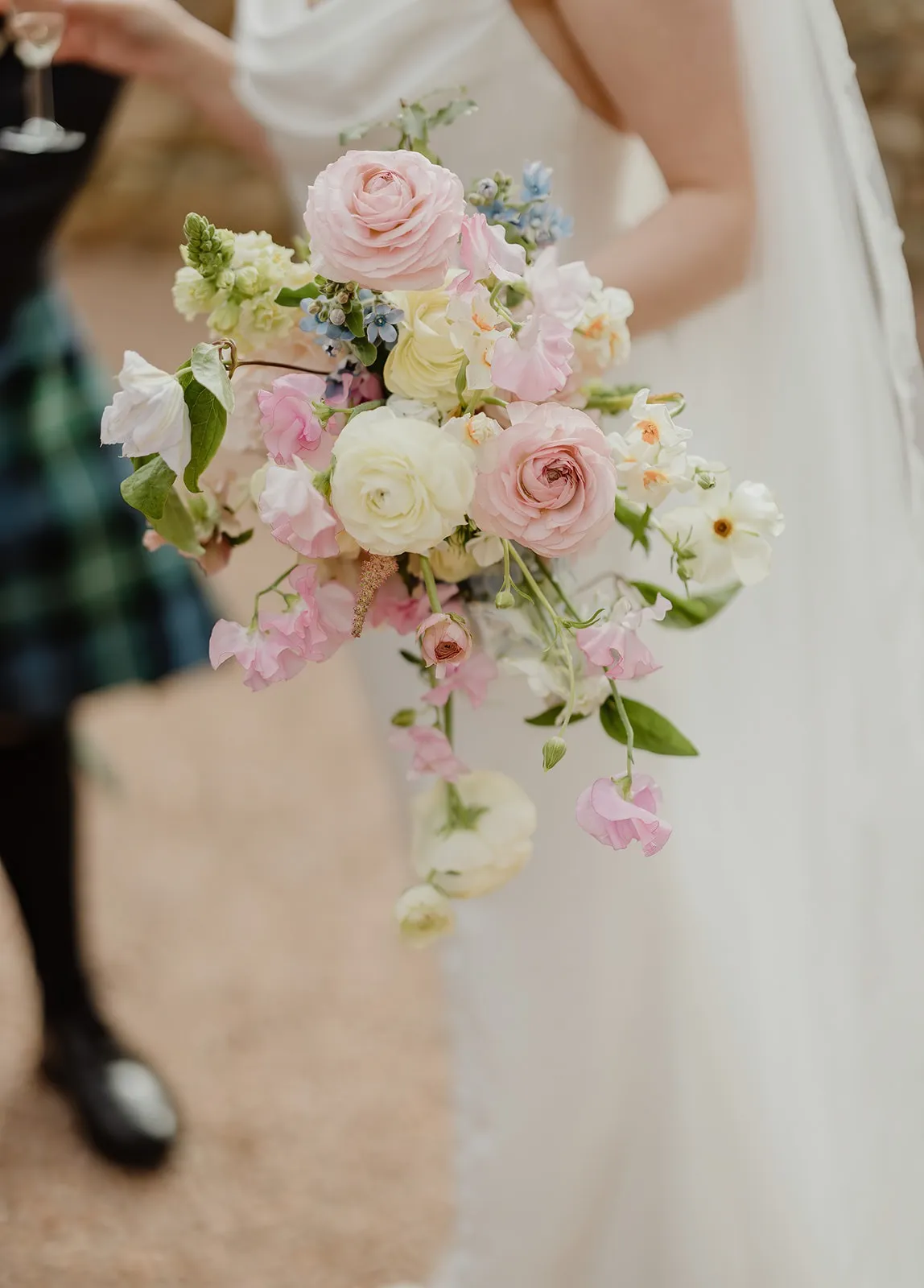 fraoch floral design bride in a white dress holding a soft pastel bouquet of pink, white, and blue flowers (roses, peonies)