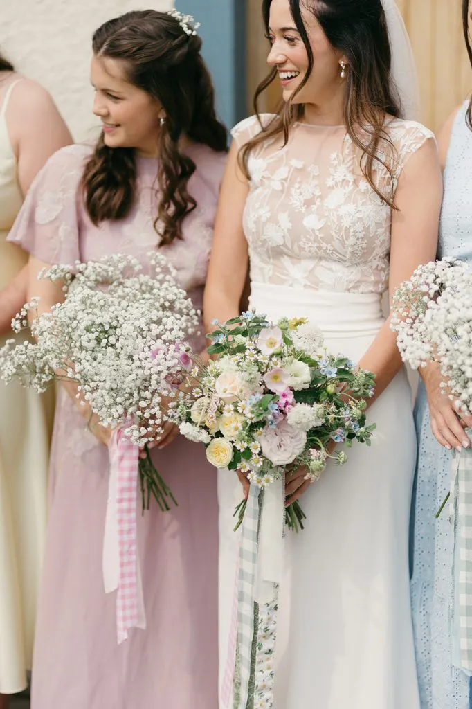 fraoch floral design bridesmaids in pastel dresses holding bouquets of white and pastel flowers, smiling together at a wedding.