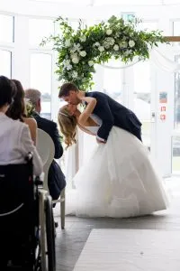 fraoch floral design bride & groom kiss in front of floral arch