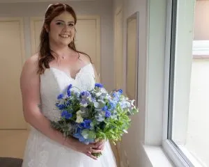 fraoch floral design bride holding a bouquet of blue summer flowers at rufflets house in st. andrews